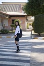 Smiling Asian young girl wear uniform with backpack walking at crossing road at school Royalty Free Stock Photo