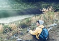 Smiling Asian young man backpackers on the grass in mountains with river enjoying their alone outdoor active lifestyle travel Royalty Free Stock Photo