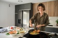 Asian young man cooking chinese or taiwanese tomato scrambled eggs at kitchen. Royalty Free Stock Photo