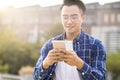 Smiling asian young man listening music and  using mobile phone while walking Royalty Free Stock Photo