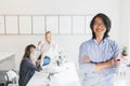 Smiling asian young man working as manager posing in office with hands crossed. Indoor portrait of handsome chinese