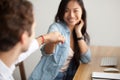 Smiling asian young woman fist bumping male colleague at work