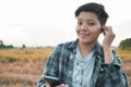 Smiling Asian young woman are short hair  listening to the podcast is a music audio mp3 player on smartphone outdoors nature Royalty Free Stock Photo