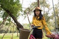 Smiling Asianwoman in vintage dress with pink bike in park