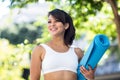 Smiling athletic woman carrying yoga mat