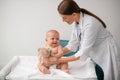 Doctor with a toy leaning towards an frightened newborn patient