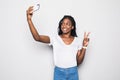 Smiling attractive african woman showing peace gesture and taking a selfie while standing isolated over gray background Royalty Free Stock Photo