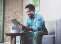 Smiling attractive bearded African man working at home while sitting on the sofa.Using digital tablet for video Royalty Free Stock Photo