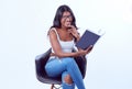 Smiling, attractive, black woman sitting on a chair and reading a book Royalty Free Stock Photo