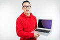 Smiling attractive brunette man demonstrates a blank laptop screen with mockup in his hands on a white studio background Royalty Free Stock Photo