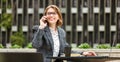 Smiling attractive businesswoman talking on mobile phone while waiting for partner or client outdoors Royalty Free Stock Photo