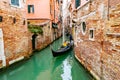 Smiling attractive Caucasian man and woman tourist couple riding in gondola. Gondolier standing on back navigating. Venice, Italy