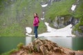 Smiling attractive female posing on rock near green rocky mountains close to artificial Vidraru lake in Romania Royalty Free Stock Photo