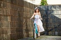 Smiling attractive girl riding blue bike down paved old city street. Royalty Free Stock Photo