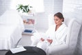 Smiling attractive girl in soft bathrobe sitting in easychair at beauty salon