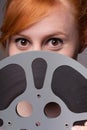 Smiling attractive redhead looking over film reel