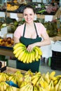smiling attractive salesgirl proposing fresh bananas in supermarket Royalty Free Stock Photo