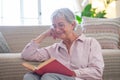 Smiling attractive senior woman relaxing sitting on the floor reading a book. Caucasian mature lady studying, learning at home Royalty Free Stock Photo