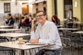 Smiling attractive stylish mature man using smart phone checking online sitting outside coffee shop Royalty Free Stock Photo