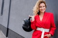 smiling attractive woman in red jacket holding motorcycle helmet