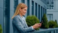 Smiling attractive woman standing outdoors holding phone checking email making order in online store happy businesswoman Royalty Free Stock Photo