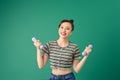 Smiling attractive young Asian woman practicing exercise with dumbell over green background