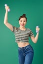 Smiling attractive young Asian woman practicing exercise with dumbell over green background