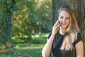 Smiling attractive young girl is phoning in the park