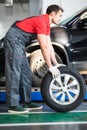 Auto mechanic carrying tire in tire store Royalty Free Stock Photo