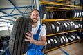 Smiling auto mechanic carrying tire Royalty Free Stock Photo