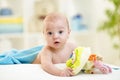 Smiling baby in a bathing towel with toy