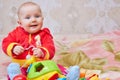 Smiling baby with blue eyes,baby smiling in a warm sweater on a bed with toys