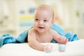 Smiling baby boy in a bathing towel with toy