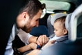 Smiling baby in child car seat going for a family roadtrip.Father fasten Safety seatbelt Royalty Free Stock Photo