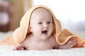 Smiling baby under soft towel. Cute child lying on bed after bathing in bedroom