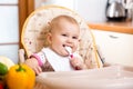Smiling baby eating food on kitchen Royalty Free Stock Photo
