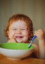 Smiling baby eating food. Launching child with spoon. Royalty Free Stock Photo