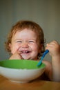 Smiling baby eating food. Launching child with spoon. Royalty Free Stock Photo