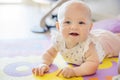 Smiling baby girl with blue eyes playing on floor mate Royalty Free Stock Photo