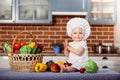 Smiling baby girl dressed in white chef toque and apron