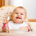 Smiling baby girl eating food on kitchen Royalty Free Stock Photo