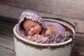 Smiling Baby Girl with Lilac Bonnet Sleeping in a Bucket Royalty Free Stock Photo