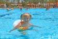 Smiling baby girl with nice plaits swimming in pool lying on inflatable circle