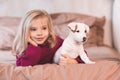 Smiling baby girl 3-4 year old lying in bed with puppy dog of jack russel terrier close up. Friendship. Royalty Free Stock Photo