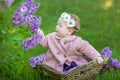 Smiling baby girl 1-2 year old wearing flower wreath, holding bouquet of lilac outdoors. Looking at camera. Summer spring time. Royalty Free Stock Photo
