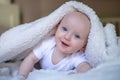 smiling baby looking at camera under a white blanket, towel Royalty Free Stock Photo