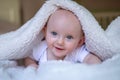 smiling baby looking at camera under a white blanket, towel Royalty Free Stock Photo