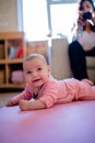 Mom Films Smiling Baby Girl Lying Down on a Pink Rug Royalty Free Stock Photo