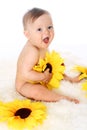 Smiling baby sitting on the fur in a full-length with sunflowers in his hands