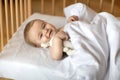 Smiling baby under blanket in wooden crib Royalty Free Stock Photo